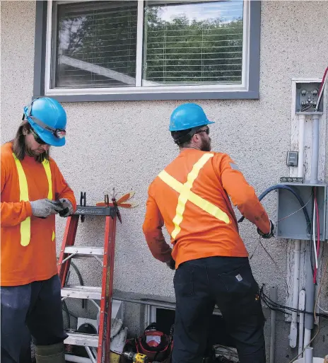  ?? TROY FLEECE ?? Alliance Energy employees Martin Doyle, left, and Mitch Harris add an expansion box under the power meter on a home in northwest Regina. The box adds one metre of extra cable to allow for ground expansion. There were 10 fires last summer due to ground...