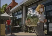  ?? DAMIAN DOVARGANES — THE ASSOCIATED PRESS ?? Fashion designer Josie Vand wears a facemask as she retrieves a bag with organic vegetables from a farm box from County Line Harvest in Los Angeles on Friday.