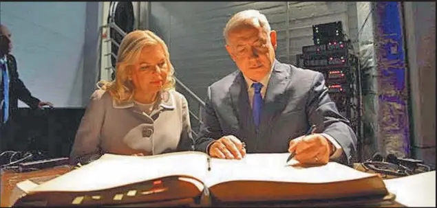  ?? AP/ISRAELI GOVERNMENT ?? In this picture released by the Israeli government, Israeli Prime Minister Benjamin Netanyahu and his wife Sara sign the visitors book at the AMIA Jewish community centre in Buenos Aires on Monday. The bombing of the Argentine-Israeli Mutual...