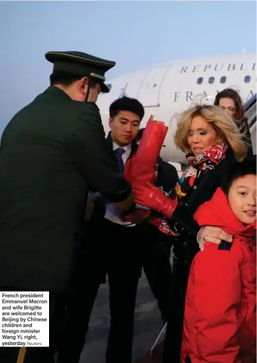  ?? Reuters ?? French president Emmanuel Macron and wife Brigitte are welcomed to Beijing by Chinese children and foreign minister Wang Yi, right, yesterday