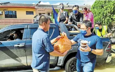  ?? ?? Sending comfort food: Ling (right) giving out boxes of tang yuan and packets of cooked meals to a flood victim as more were being distribute­d by the crsm volunteers.
