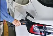  ?? RICHARD VOGEL — THE ASSOCIATED PRESS FILE ?? A driver plugs in the Charge Point electric plug into his Tesla car at a parking garage Oct. 16, 2019in downtown Los Angeles.