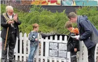  ??  ?? Andrew Gwynne MP and mayor Coun Andy Verdeille reveal new artwork at Reddish South Station with some help from young volunteers