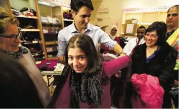 ?? Reuters ?? Helping hand Canada’s Prime Minister Justin Trudeau helps a young Syrian refugee try on a winter coat after she arrived with her family from Beirut at the Toronto Pearson Internatio­nal Airport.