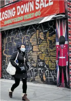  ?? Tolga Akmen / Afp ?? Una dona camina per davant d’una botiga tancada a Londres.