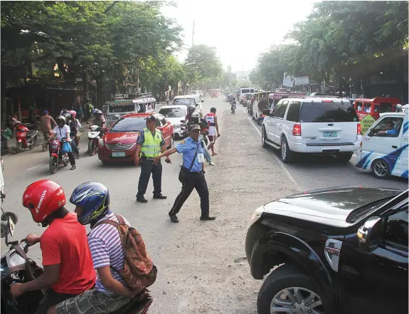  ?? JOY TORREJOS ?? A Cebu City Transporta­tion Office enforcer is assisted by a policeman in directing the traffic on N. Bacalso Avenue where an ongoing underpass project is causing monstrous traffic in Mambaling area.