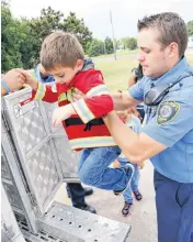  ?? [PHOTOS BY DOUG HOKE, THE OKLAHOMAN] ?? A firefighte­r lifts Benny McCain, 5, into the rescue ladder truck Tuesday at Oklahoma City Fire Station 30.