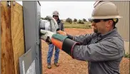  ?? FELICIA FONSECA / AP ?? Ken Wagner, a journeyman lineman with Piqua Power System in Piqua, Ohio, installs an electric meter at a home in Kaibeto, Arizona, on the Navajo Nation, as his coworker, Kevin Grinstead, looks on.