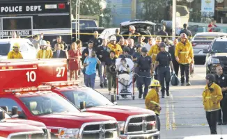  ??  ?? Los Angeles officials escort a woman being evacuated by emergency personnel after a gunman held hostages inside a Trader Joe’s store, Los Angeles, July 21.