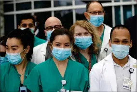  ?? AP PHOTO BY MARCIO JOSE SANCHEZ ?? Hospital personnel stand outside Providence St. John’s Medical Center on Friday, April 17, in Santa Monica, Calif. The hospital was holding a news conference to announce the recovery of a police officer from coronaviru­s. The hospital suspended ten nurses from their jobs earlier in the week after they refused to care for COVID-19 patients without being provided protective N95 face masks.