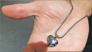  ??  ?? Colin Barrett of Barrett’s Funeral Home in St. John’s holds a silver pendant that can hold a small portion of ashes.