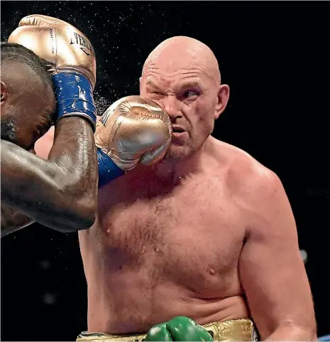  ?? MARK TERRILL/AP ?? American Deontay Wilder lands a left hook to the face of Englishman Tyson Fury during their WBC heavyweigh­t title fight in Los Angeles on Sunday.