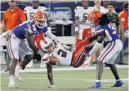  ?? JOHN RAOUX/ASSOCIATED PRESS ?? Miami wide receiver K.J. Osborn fumbles the ball as he is hit by Florida linebacker Jon Greenard, left, and defensive back Shawn Davis during the second half Saturday.