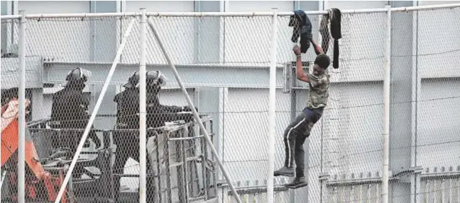  ?? FOTOS ANTONIO SEMPERE/EP ?? Varios agentes se acercan a un inmigrante que intentó saltar la valla que separa Ceuta de Marruecos