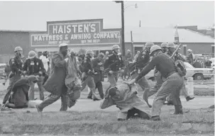  ?? ASSOCIATED PRESS ?? On March 7, 1965, a state trooper swings a billy club at John Lewis, right foreground, chairman of the Student Nonviolent Coordinati­ng Committee, to break up a protest march.