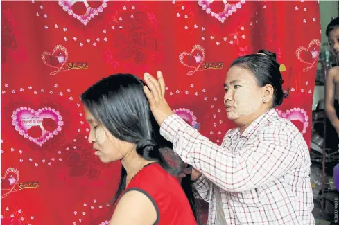  ??  ?? Thidar Win cuts Nwe Yee Win’s hair, which she purchased for $18 in Yangon.