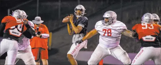  ?? L.E. Baskow Las Vegas Review-journal @Left_eye_images ?? UNLV quarterbac­k Armani Rogers looks for an open receiver while receiving protection from offensive lineman Justin Polu (78) during Saturday night’s scrimmage.