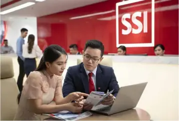  ?? Courtesy of SSI
Photo ?? A trader talks to a customer at a trading office of SSI.