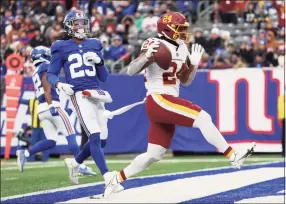  ?? Dustin Satloff / Getty Images ?? Washington’s Antonio Gibson, right, runs into the end zone for a touchdown in the fourth quarter against the Giants on Sunday at MetLife Stadium.