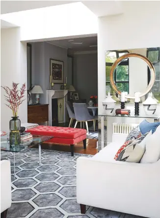  ??  ?? SITTING ROOM
A brightly coloured velvet ottoman (right) acts as a graceful break between the dining and sitting areas, and is an excellent contrast to the rug. Its warm pink tones are echoed in a large-scale oil painting depicting a busy square in...