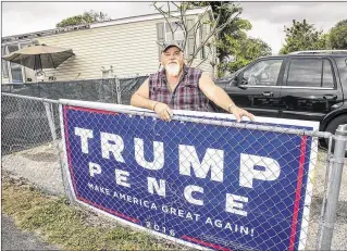  ?? PHOTOS BY LANNIS WATERS / THE PALM BEACH POST ?? Mike Bagenstos stands behind a Trump-Pence sign hanging on a fence at his home west of Boca Raton. Bagenstos is upset that the county is ordering him to take down the sign, especially since a neighbor is flying a Ku Klux Klan flag without any...