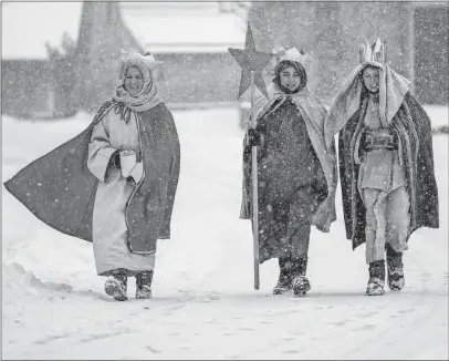  ?? [THOMAS WARNACK/DPA] ?? Choral singers in traditiona­l costumes walk through snow in Eglingen in southern Germany on Saturday. Heavy snow caused travel chaos in parts of Germany and Austria, and more snow is in the forecast for the coming days.
