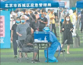  ?? AFP ?? A health worker wearing a protective suit takes a swab test sample from a woman at Guang’an Sport Centre for people who visited or live near the Xinfadi Market in Beijing.