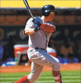  ?? Jason O. Watson / Getty Images ?? Boston’s Brock Holt hits an RBI double against Oakland during the seventh inning on Sunday.