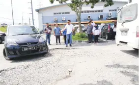  ??  ?? Abdul Rahman looking at a vehicle maneuverin­g through the damaged road in Indah Permai.