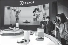 ?? PROVIDED TO CHINA DAILY ?? Visitors look at robotic vacuum cleaners on display at Ecovacs’ booth during the Appliance & Electronic­s World Expo held in Shanghai in March.
