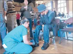  ??  ?? Catherine Jacobs, a podiatry resident at St. Francis Hospital and Medical Center, ties Rahan Rust’s new shoes Saturday.