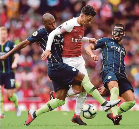  ?? [ FOTO AFP ] ?? Ozil (tengah) diasak dua pemain City, Fernandinh­o (kiri) dan Ilkay Gundogan pada aksi Liga Perdana Inggeris di Stadium Emirates, kelmarin.