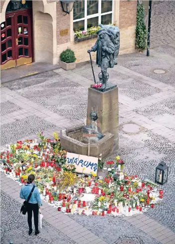  ?? FOTO: DPA ?? Kerzen und Blumen liegen am Tatort vor dem Denkmal des Kiepenkerl­s. Auch die Gaststätte im Hintergrun­d trägt diesen Namen.