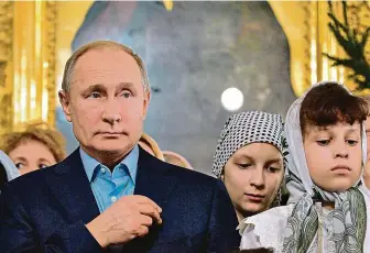  ?? FOTO ČTK/AP ?? Křižující se prezident. Šéf Kremlu Vladimir Putin v pondělí zavítal na půlnoční mši do Spaso-preobražen­ského chrámu v Petrohradu. Tam byl – podle svých slov – v roce 1952 jakožto syn člena komunistic­ké strany tajně pokřtěn.