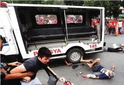  ??  ?? MANILA: Protesters lie on the ground after being hit by a police van during a rally in front of the US embassy. —AFP