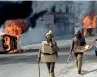  ?? AP ?? Policeman walk past vehicles set on fire by a mob during a protest in Jammu on Friday. —