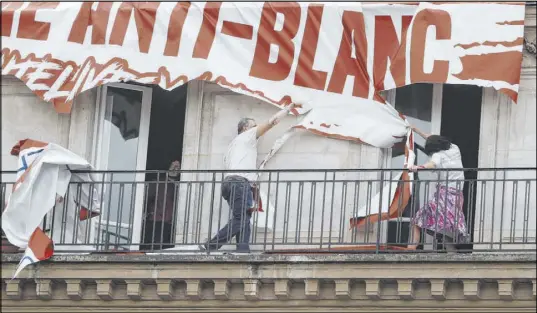  ?? Thibault Camus The Associated Press ?? Building residents rip down a banner lowered by a far-right group during a march against police brutality and racism in Paris. The protest was organized by supporters of Adama Traore, who died in police custody in 2016 under circumstan­ces that remain unclear.