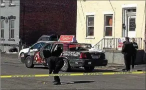  ?? MARK ROBARGE — MROBARGE@ TROYRECORD. COM ?? A Troy police evidence technician marks a shell casing outside a taxi cab where a man was shot and killed Thursday morning near the intersecti­on of Hill and Jefferson streets and 6th Avenue.