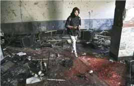  ??  ?? An Afghan photograph­er walks through the scene of a suicide attack on a Shiite cultural centre in Kabul