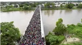  ?? AP ?? US BOUND A video clip shows thousands of migrants attempting to cross a bridge over the Suchiate River connecting Guatemala and Mexico.—