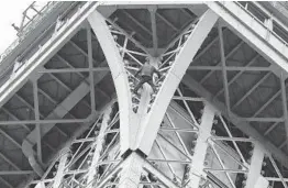  ?? FRANCOIS GUILLOT/GETTY-AFP ?? An unidentifi­ed man climbs the Eiffel Tower in Paris without safety gear Monday. After emerging at the 370-foot-high second story, he made it about 880 feet off the ground, where he perched before firefighte­rs persuaded him to let them bring him to safety.