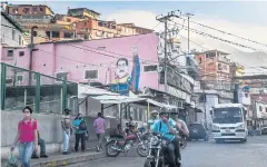  ?? AFP ?? Passers-by walk past a graffiti of President Nicolas Maduro in Caracas on Wednesday.