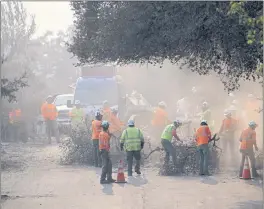  ?? MINENNA PHOTOGRAPH­Y ?? Clean up crews work the day after the Cache Fire. Clean up began with PG&E replacing poles, Loggers Unlimited cutting down trees that are still burning and some that are just too hazardous to remain standing.