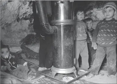  ?? AAMIR QURESHI/ AFP/GETTY IMAGES ?? A Syrian family, who evacuated their home due to shelling, gather inside a cave where they have taken refuge.