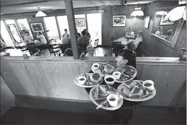  ?? NWA Democrat-Gazette/J.T. WAMPLER ?? Rayna Warrix hustles a tray of food to a table Wednesday at the Restaurant on the Corner. The restaurant has been sold and its future is uncertain.