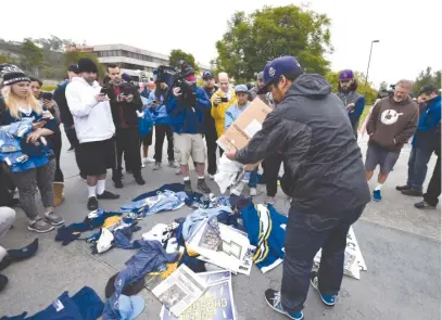  ??  ?? A former Chargers fan dumps memorabili­a in front of the team’s headquarte­rs after the move to Los Angeles was announced. | AP
