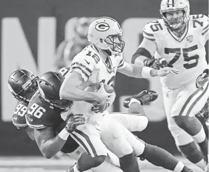  ?? DAN POWERS/USA TODAY NETWORK-WISCONSIN ?? Packers quarterbac­k Aaron Rodgers is brought down by Vikings end Danielle Hunter (99) and tackle Tom Johnson (96) in the second quarter.