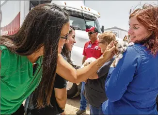  ?? STEPHEN SPILLMAN / FOR AMERICAN-STATESMAN ?? Bastrop H-E-B store director Aris Cox pets a cat held by Director of Animal Services Ashley Hermans at the Bastrop County animal shelter Monday. “This is the best Monday I’ve ever had in my life,” Hermans said after H-E-B donated supplies and $5,000.