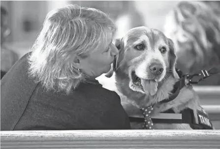  ?? ?? Lori Lawrence of Oriana House gives a kiss to Tank, a therapy dog, during a Turning Point Program graduation ceremony in Akron.