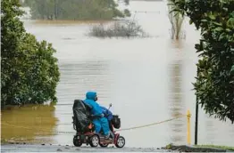  ?? MARK BAKER/AP ?? A woman looks over inundated farmland Monday near Sydney as Australia’s largest city braces for its fourth and possibly worst round of flooding in 18 months.